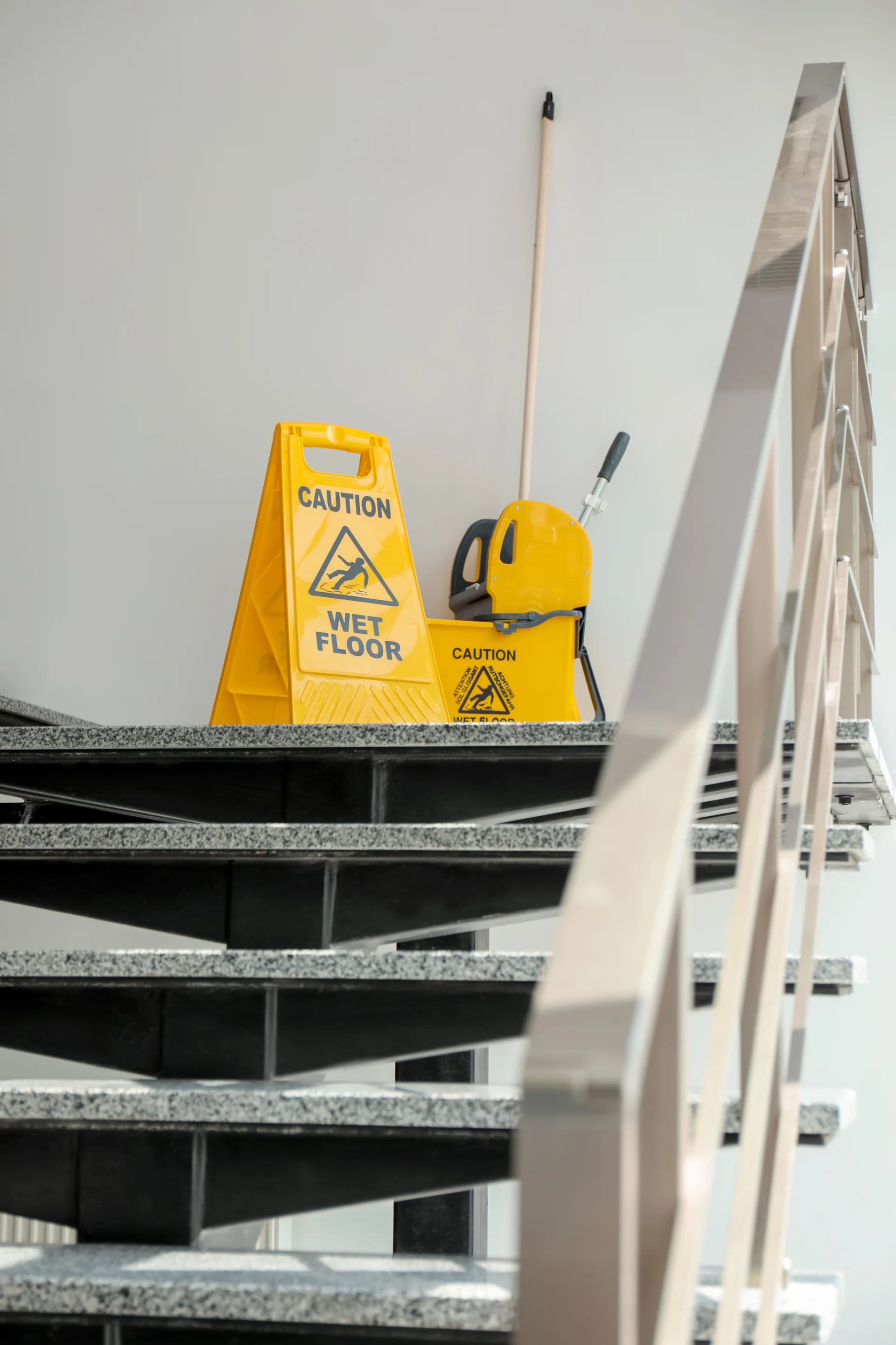 Warnschild und Wischmopp auf frisch gereinigter Treppe