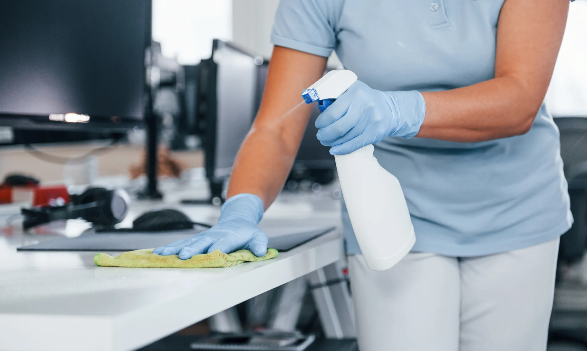 Reinigungskraft mit Schutzhandschuhen bei der Büroreinigung